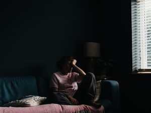 Depressed person sitting on couch experiencing loneliness.